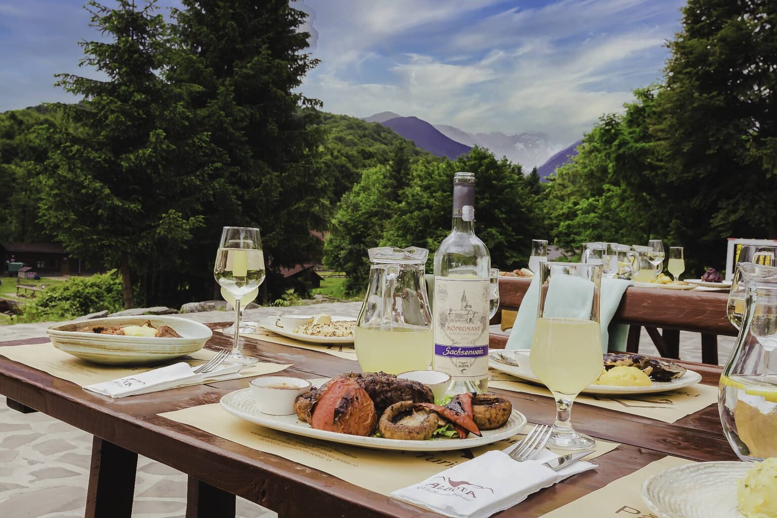 Carne la grătar cu ciuperci, vin alb și limonadă, pe terasa cu vedere spre munți