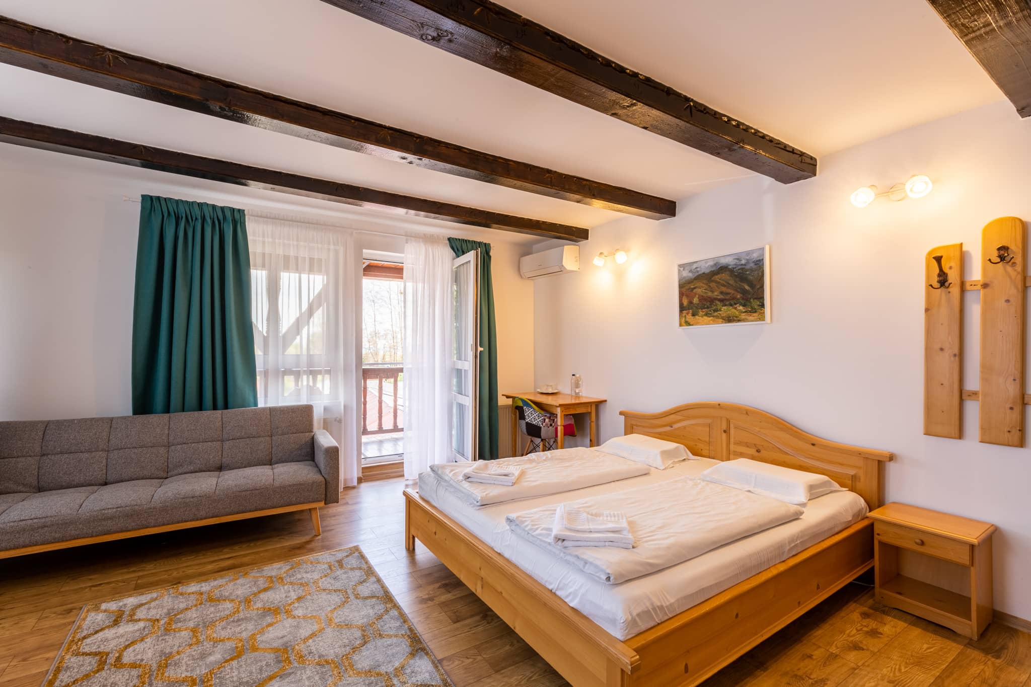 Zimmer mit Holzbalkendecke, Doppelbett und Sofa