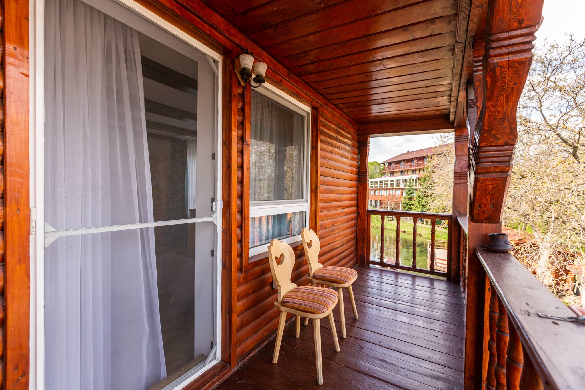 Holzbalkon mit geschnitzten Stühlen, mit Blick auf die Becken und das Restaurant