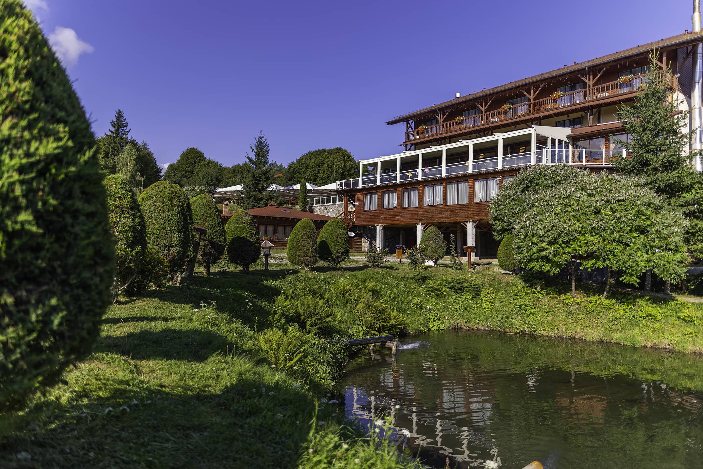 Das Haupthaus des Complex Albota mit Glasveranda, hinter dem Teich