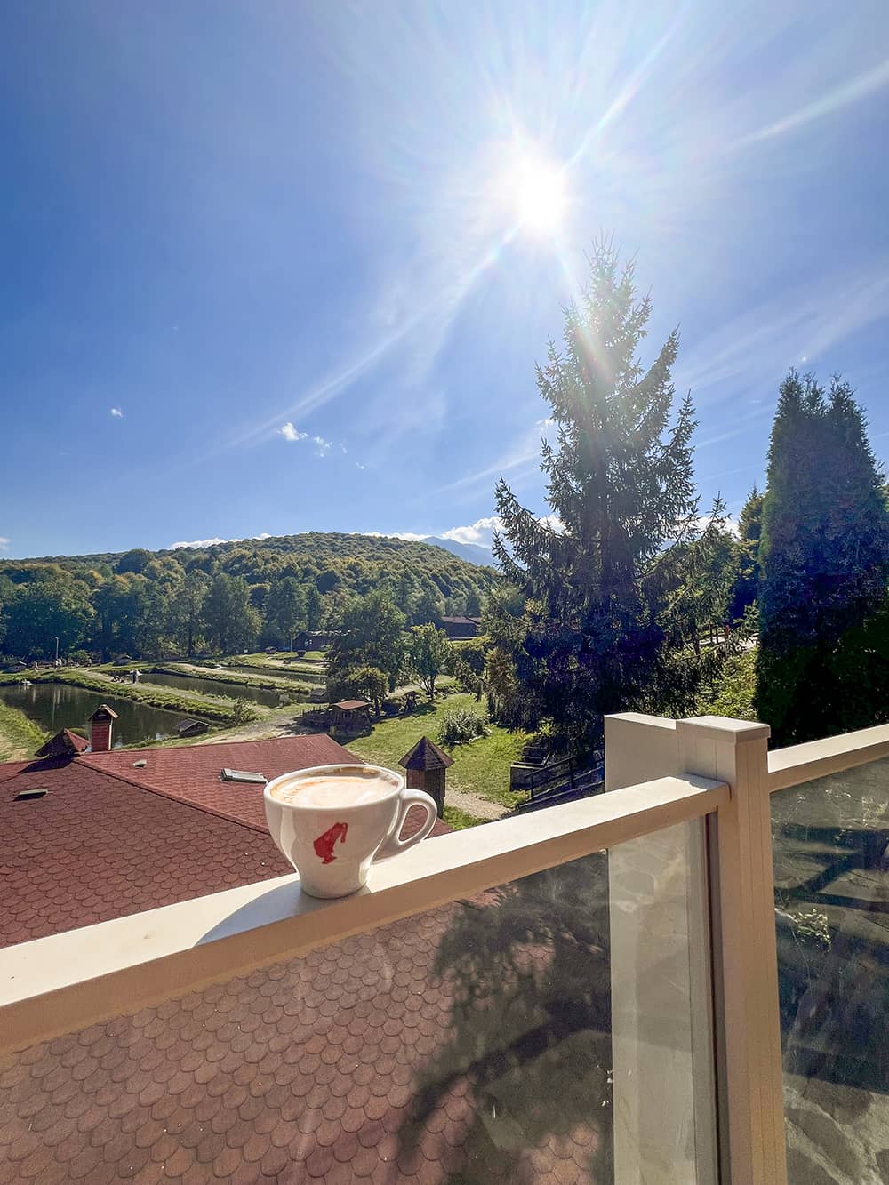 Cafea pe balustrada balconului, cu vedere spre bazinele cu păstrăvi