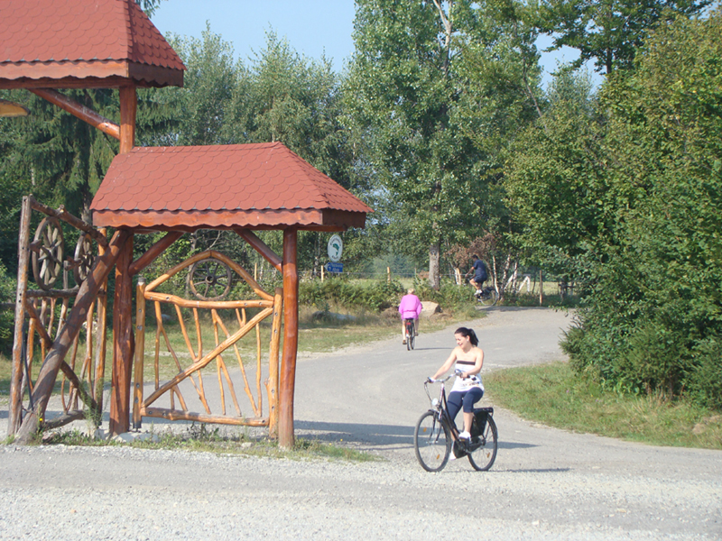 Eine Radfahrerin fährt am geschnitzten Holztor vorbei