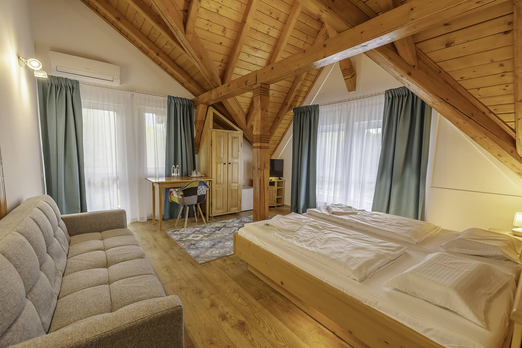 Dachzimmer mit sichtbarem Holzgebälk und Doppelbett