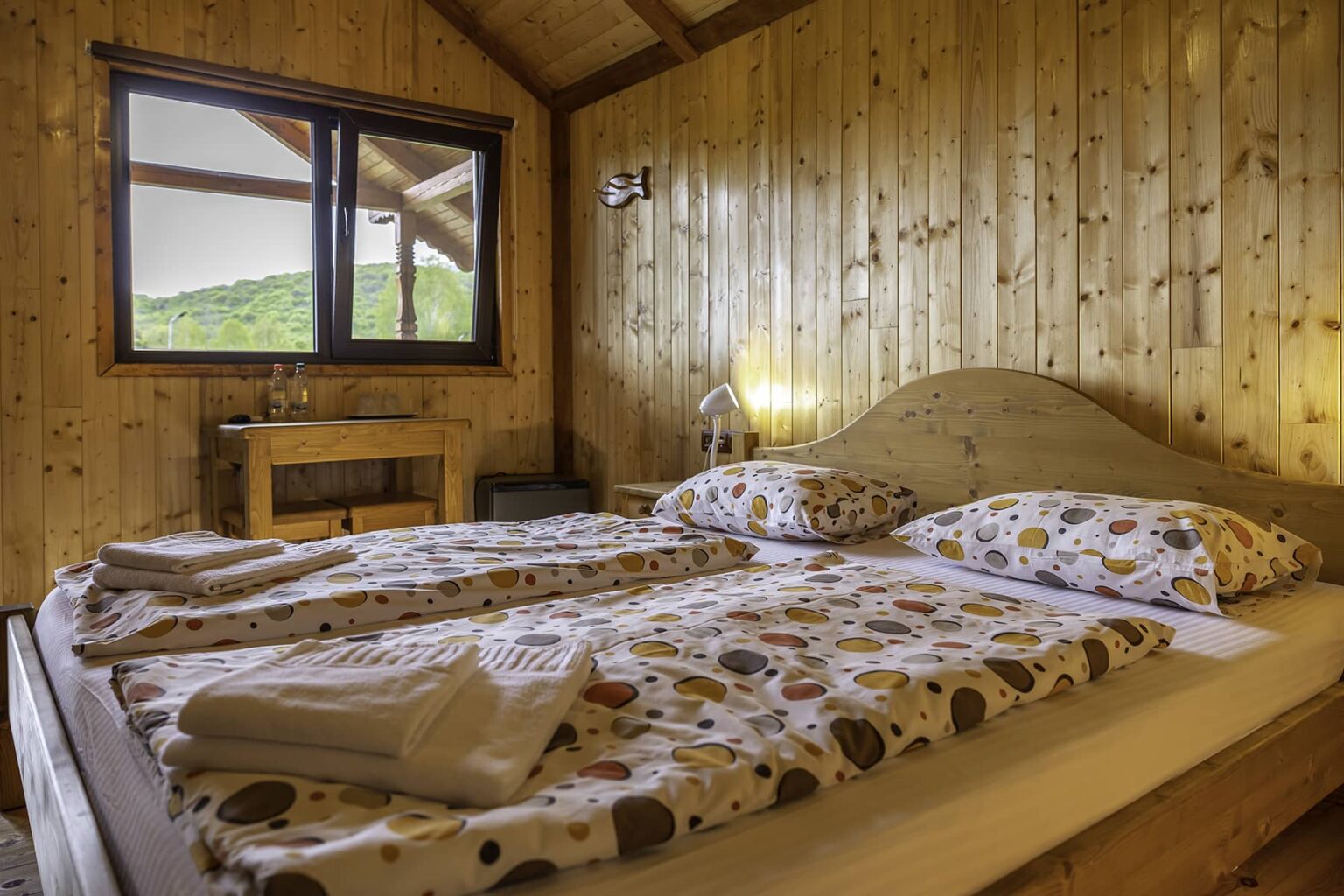 Inside a wooden cabin, with a double bed and pine panelling