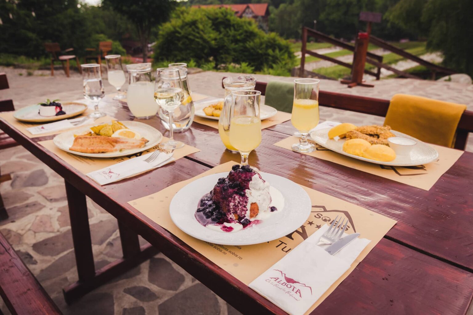 Papanași cu smântână și dulceață, lângă pahare cu limonadă