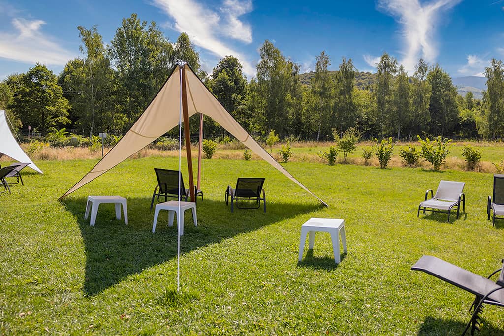 The camping area on mown grass, with a parasol and loungers
