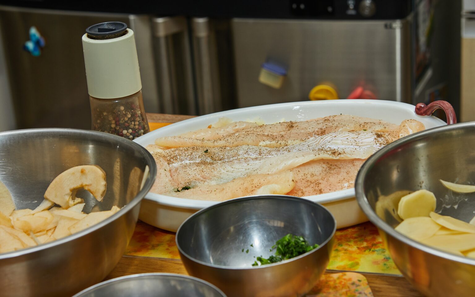 Gewürztes Fischfilet in der Form, dazu Kartoffeln und Apfelscheiben