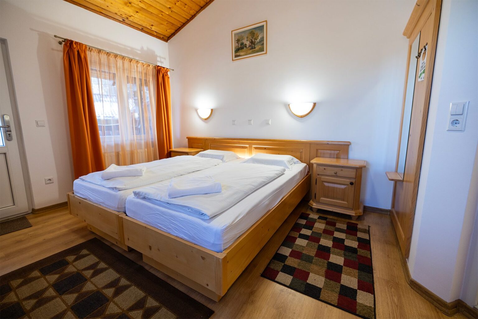 Hütte B: Schlafzimmer mit Doppelbett aus Holz und traditionellem Teppich