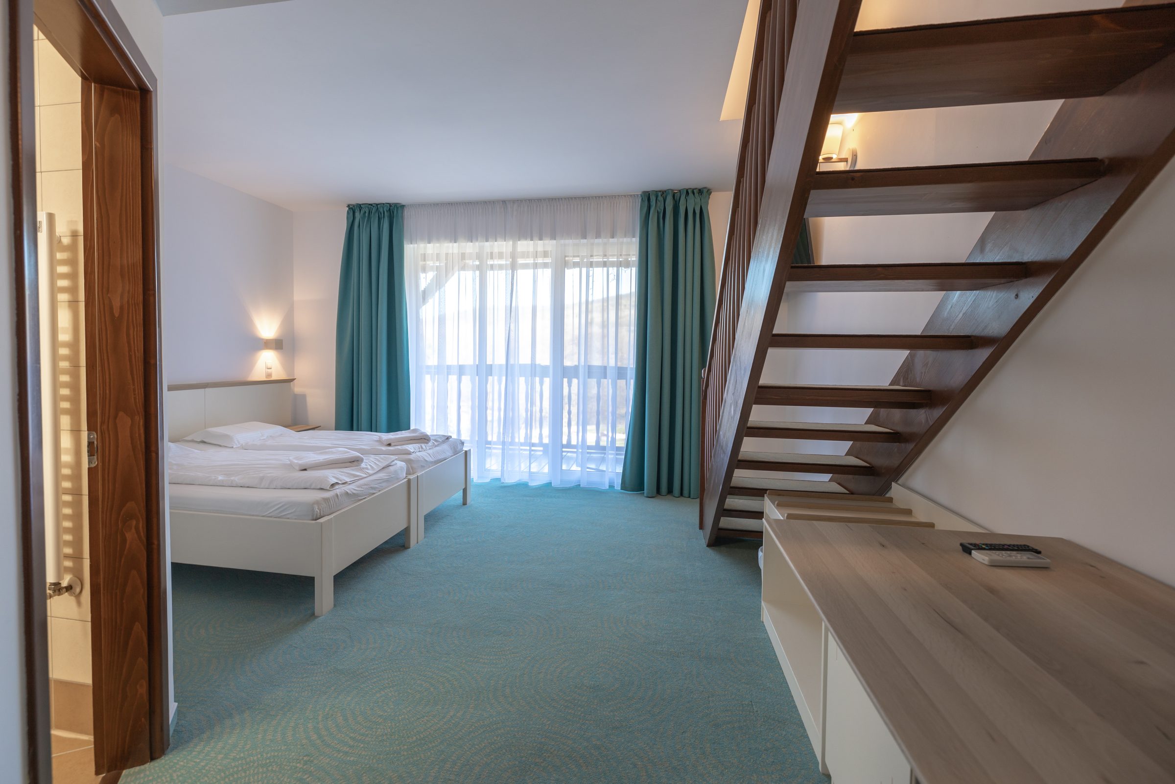 Junior Suite: the bedroom with the wooden staircase to the loft and the balcony door